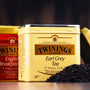 Twinings Earl Grey and English Breakfast - 2 tea caddies behind each other, with a pile of black tea in front,